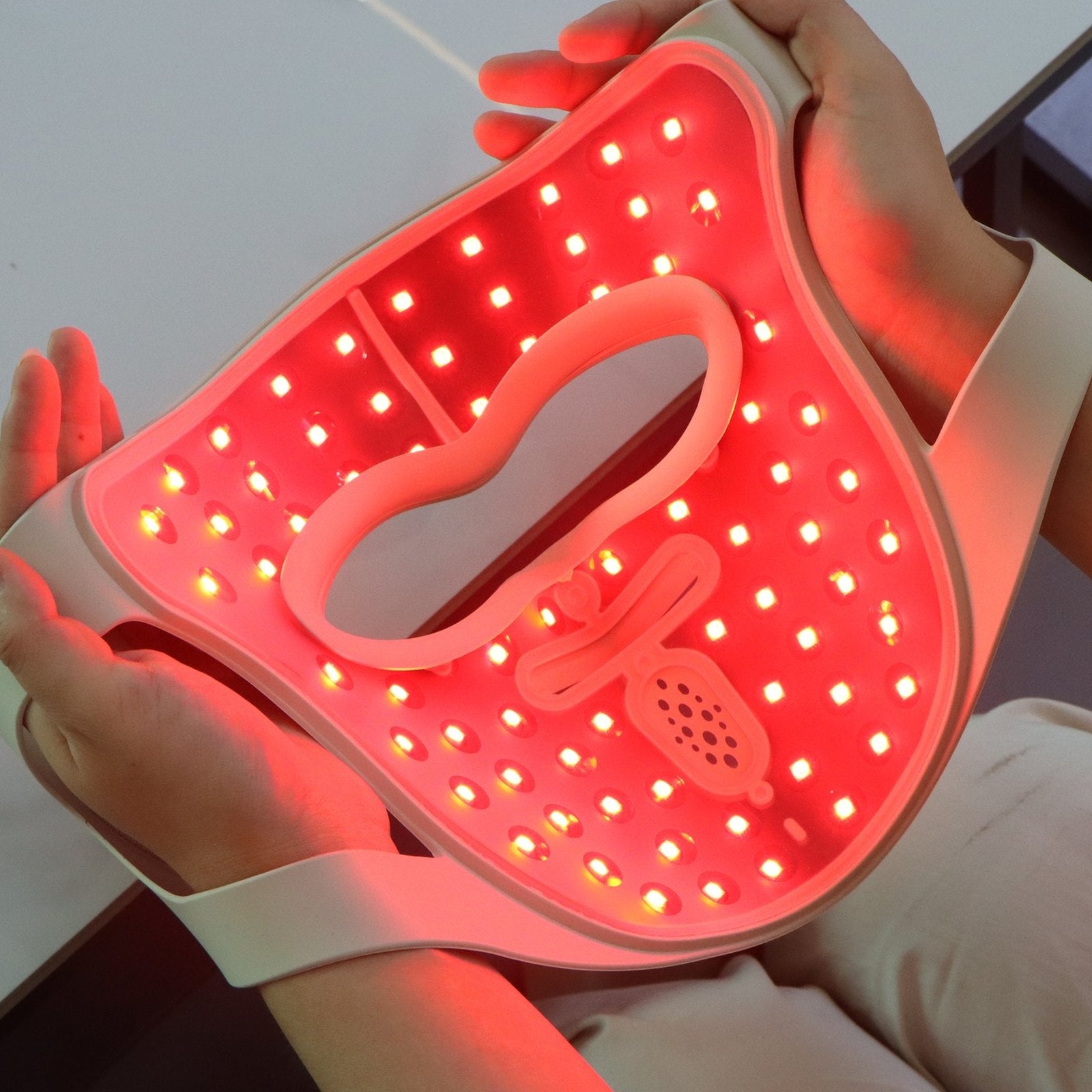 The P.s. I Love You from the inside, red mode — the full-face LED array lit, held in two hands