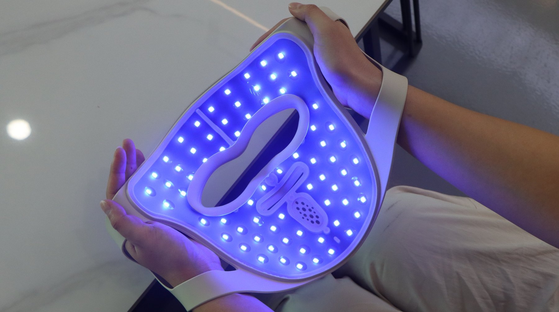 The P.s. I Love You from the inside, blue mode — the full-face LED array lit, held in two hands